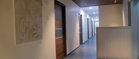 A modern hallway with a wooden door, a reception desk, and wall art.