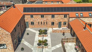 A courtyard with a central pathway, surrounded by buildings with brick facades and orange-tiled roofs. - The Hay Barn (Thirsk)
