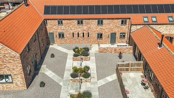 A courtyard with a central pathway, surrounded by buildings with brick facades and orange-tiled roofs.