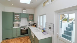 Eine moderne Küche mit grünen Schränken, weißen Arbeitsplatten und einem eingebauten Backofen.