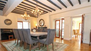 A dining room with a wooden table, grey upholstered chairs, a chandelier, and a floral rug.