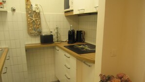 A small kitchen with white tiled walls, a wooden countertop, a coffee maker, and a decorative item with flowers. - Retreat in Grado Just 100m From the Beach (Grado)