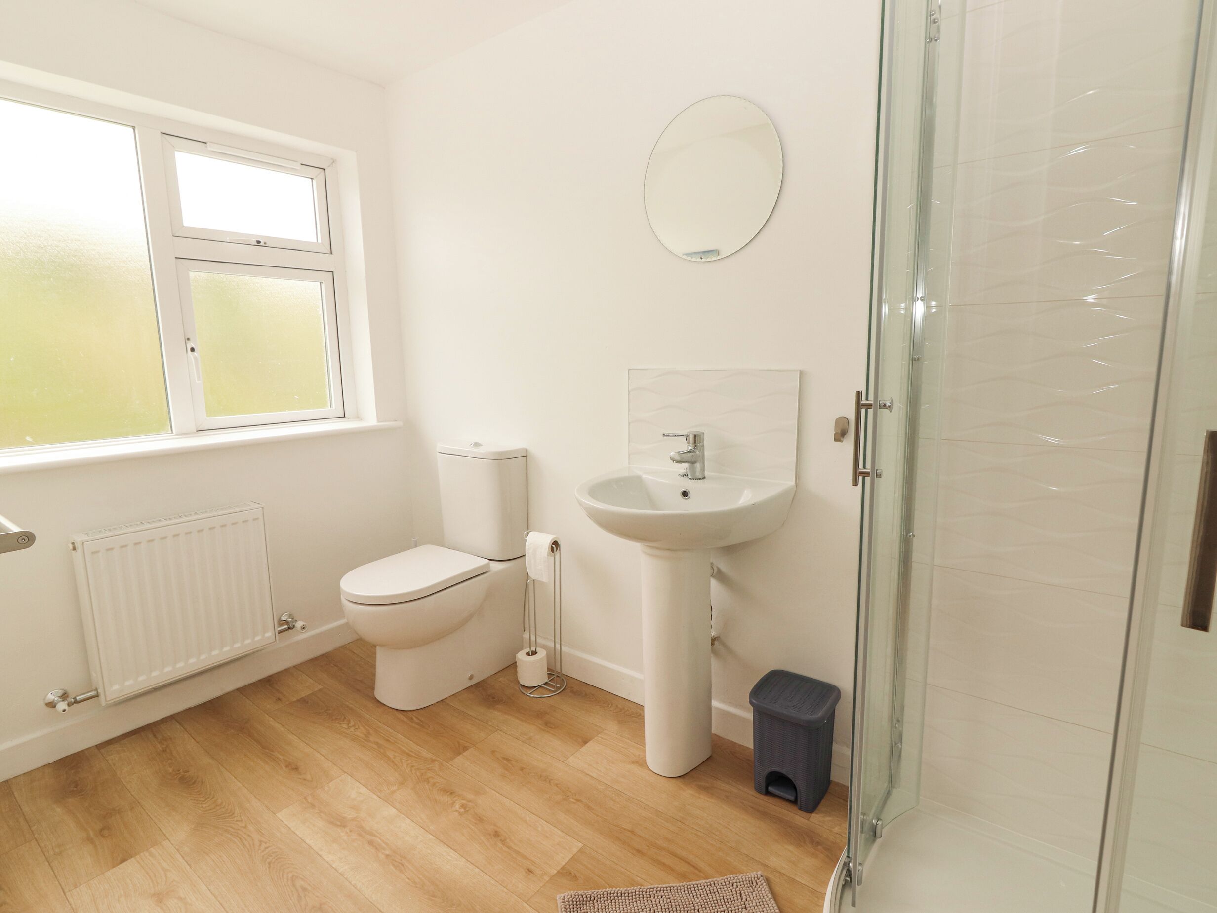 A modern bathroom with a toilet, sink, and glass shower enclosure.