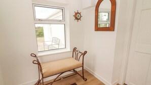 Une pièce avec un banc, une fenêtre, un miroir en bois et une porte.