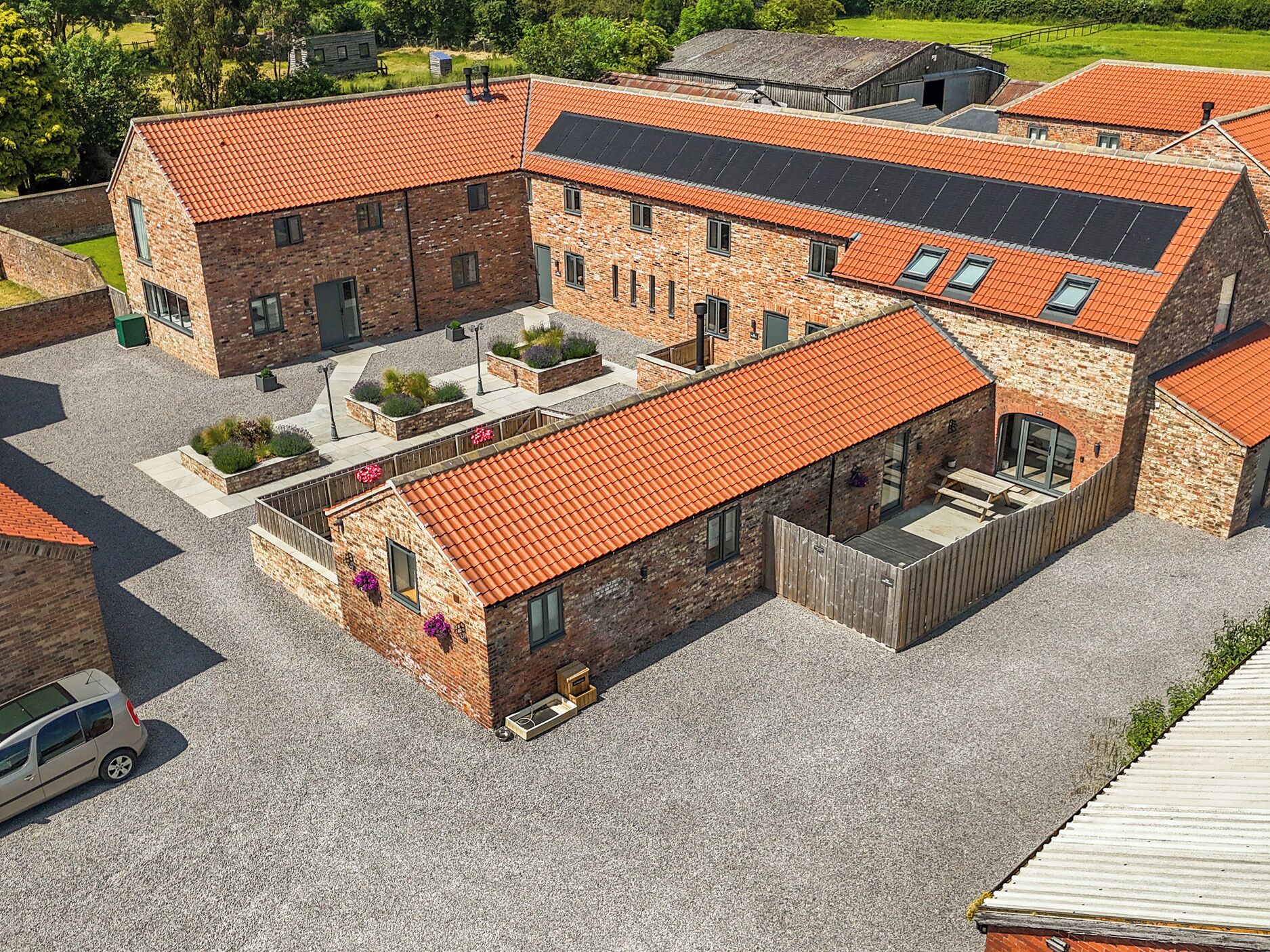 A multi-story building with a red-tiled roof, brick walls, and a courtyard with planters.