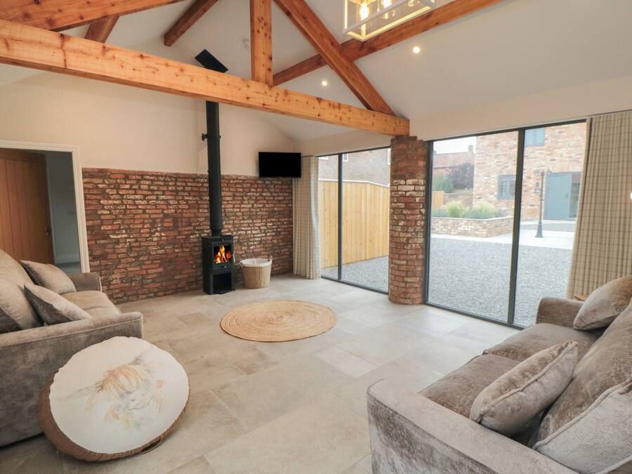 Un amplio salón con chimenea, asientos cómodos y ventanas grandes.