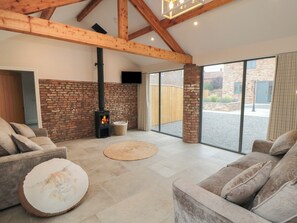 A spacious living area with a fireplace, comfortable seating, and large windows. - The Mill House (Thirsk)