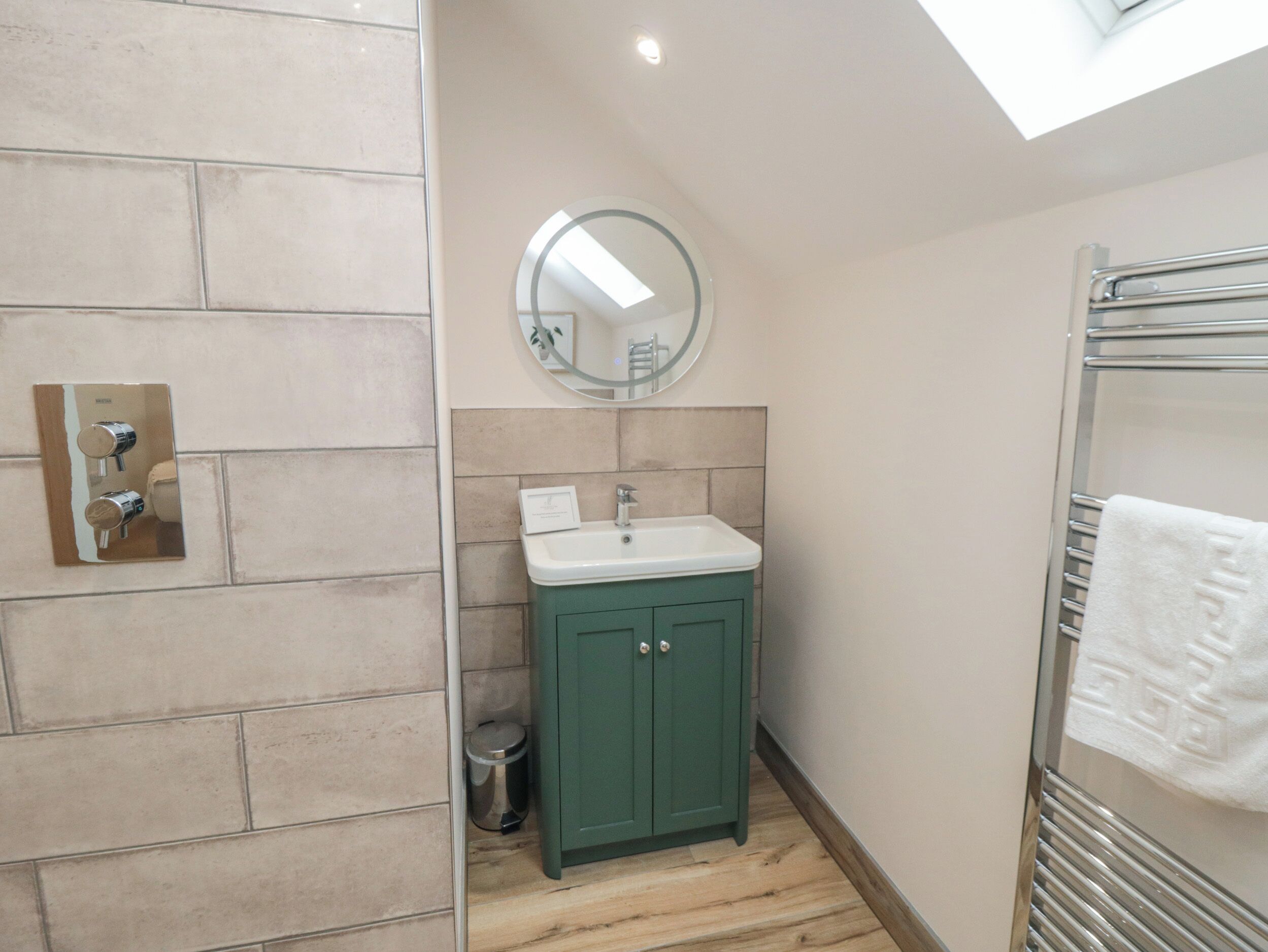 A bathroom with a green cabinet, a white sink, a mirror, and a towel rack.
