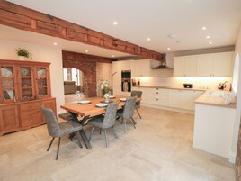Una cocina amplia con una mesa de comedor de madera, cuatro sillas y una pared de ladrillo.