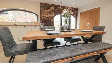 Een eetgedeelte met een houten tafel, grijs gestoffeerde stoelen en een bank.
