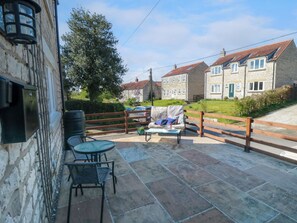 A patio area with stone flooring, outdoor furniture, and a view of neighboring houses. - Lilac Cottage (York)