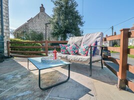 Un área de estar al aire libre con una mesa, sillas y una botella de vino.