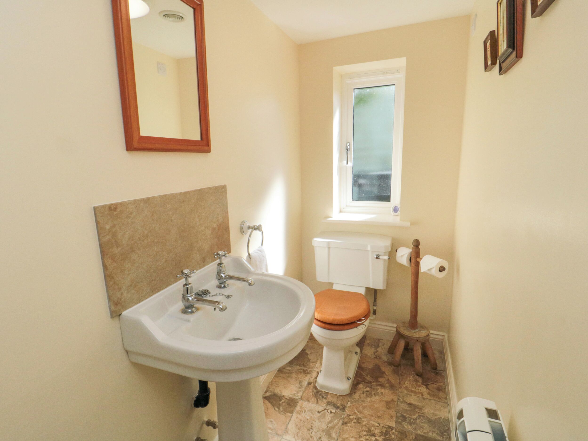 A bathroom with a sink, toilet, and window.