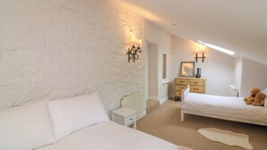 A bedroom with two beds, a dresser, a mirror, and a teddy bear. - Ellenor (Kingsbridge)