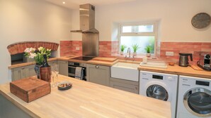 A modern kitchen with a built-in oven, stainless steel range hood, and a window with a view. - Ellenor (Kingsbridge)