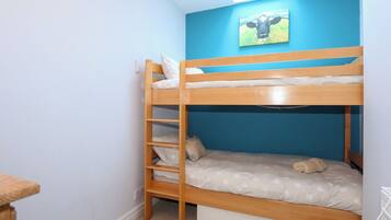 A bunk bed room with a skylight, a blue wall, and a cow picture.