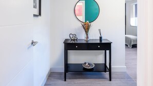 A black console table with a round mirror, a vase with dried flowers, and a small bowl.