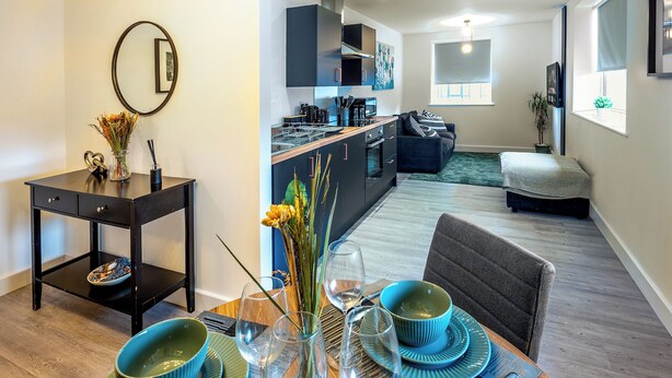 A compact living space with a dining area, kitchenette, and a small bedroom.