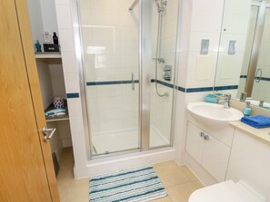 Een moderne badkamer met een douche met glazen wand, een wit wastafel en een spiegel.