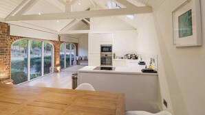 Een moderne keuken met een centraal eiland, grote ramen en uitzicht op een tuin.