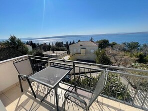 Ein Balkon mit Tisch und Stühlen mit Blick auf ein Gewässer und entferntes Land.
