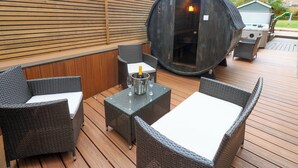 An outdoor patio with wicker furniture, a large barrel, and a grill. - The Miners Hall Retreat (Stanley)