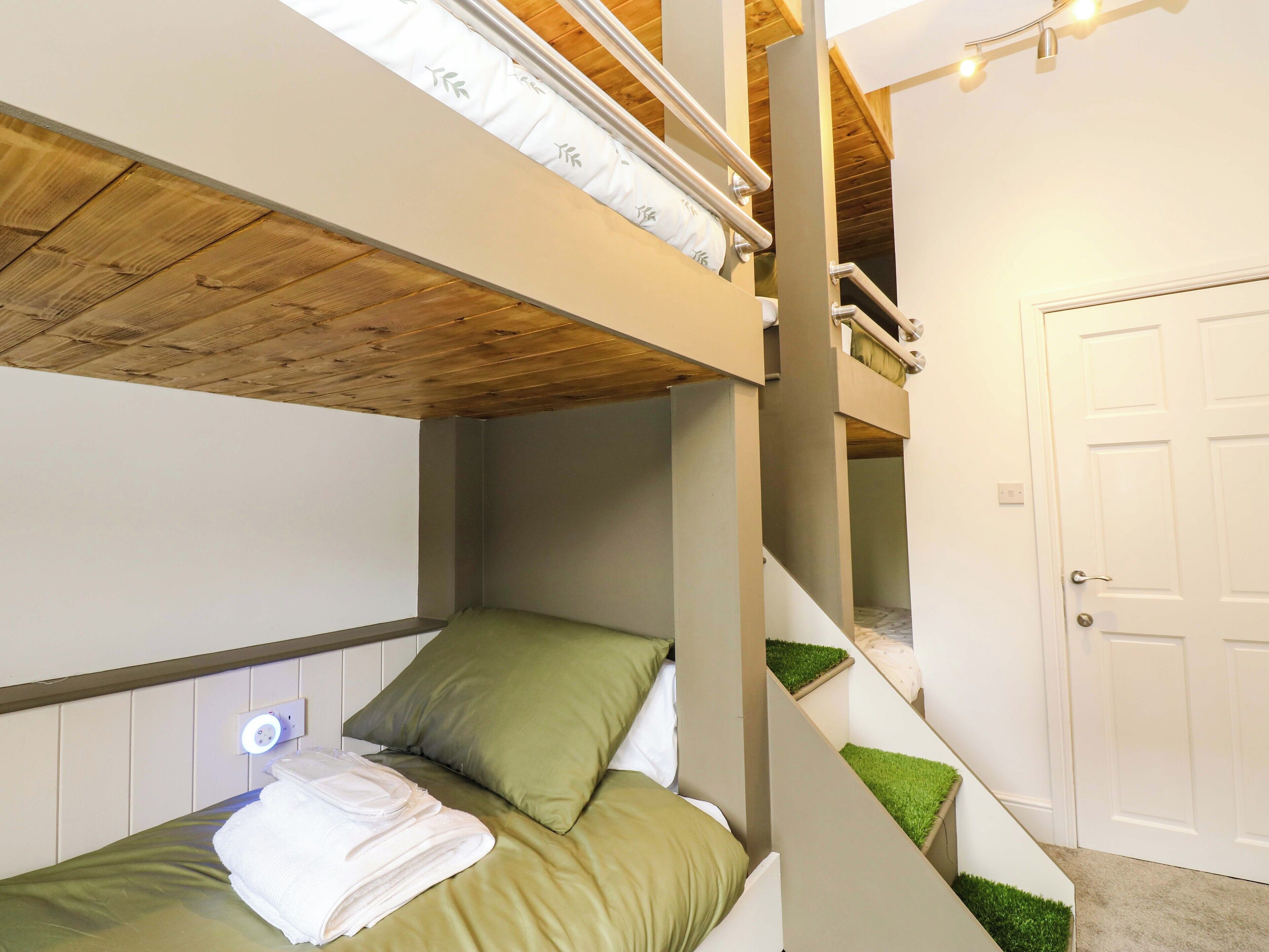 A bunk bed with a wooden ceiling and a white door in the background.