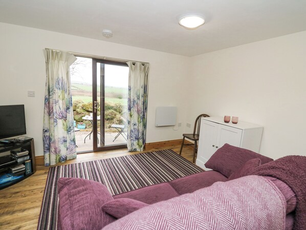 A room with a bed, a TV, a desk, and a view of the outdoors. - Y Gweithdy Rhos Eirin (Clynderwen)