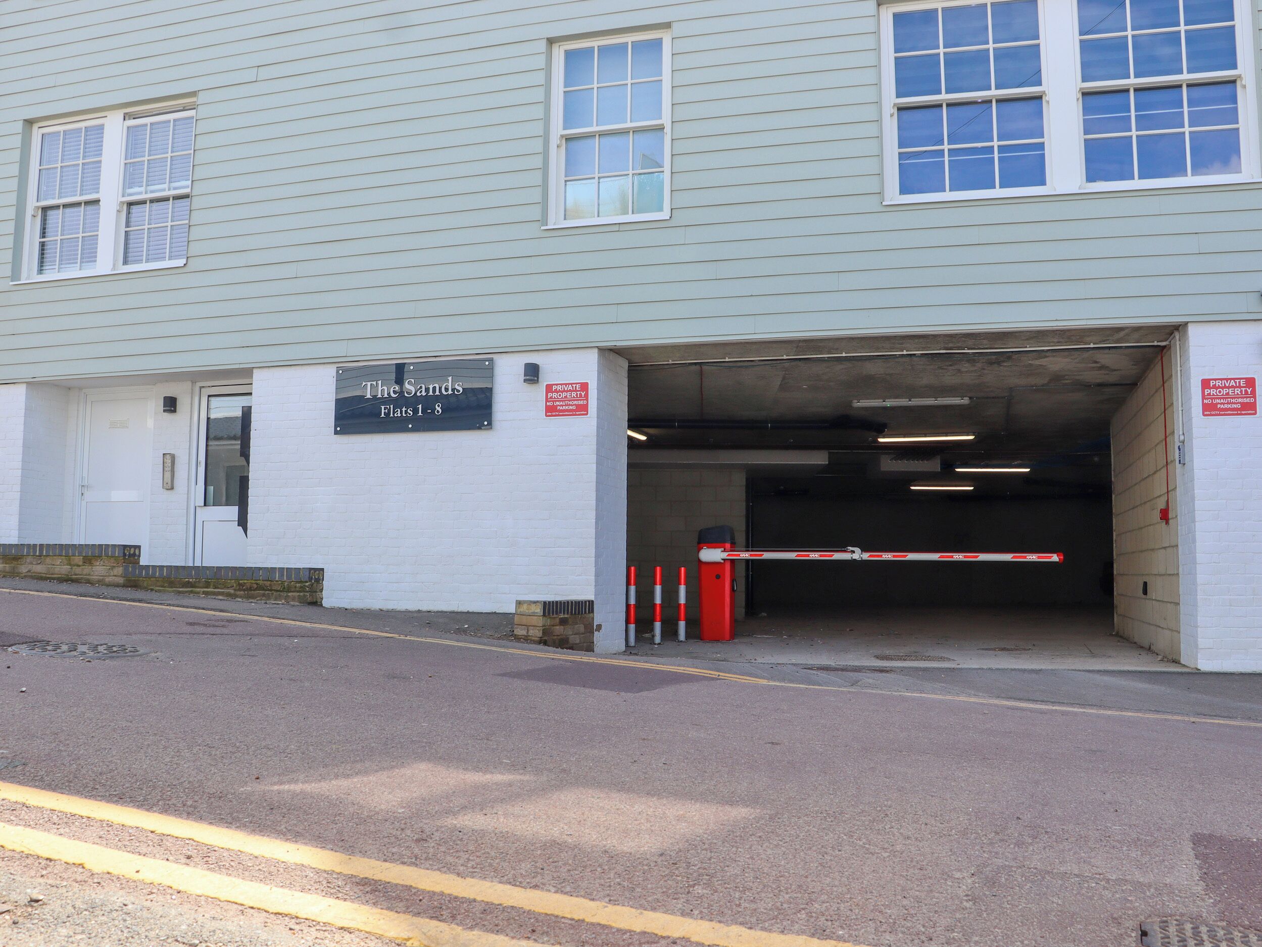 A building with a sign reading "The Sands Flats 1-8" and a "PRIVATE PROPERTY NO UNAUTHORISED PARKING" sign.