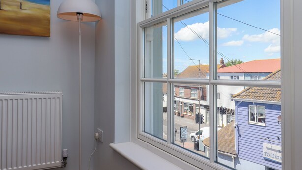 A room with a large window, a radiator, and a floor lamp. - The Seven Sands (Romney Marsh)