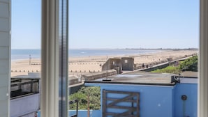 A view of a beach from a window, with a clear sky and calm sea. - The Seven Sands (Romney Marsh)