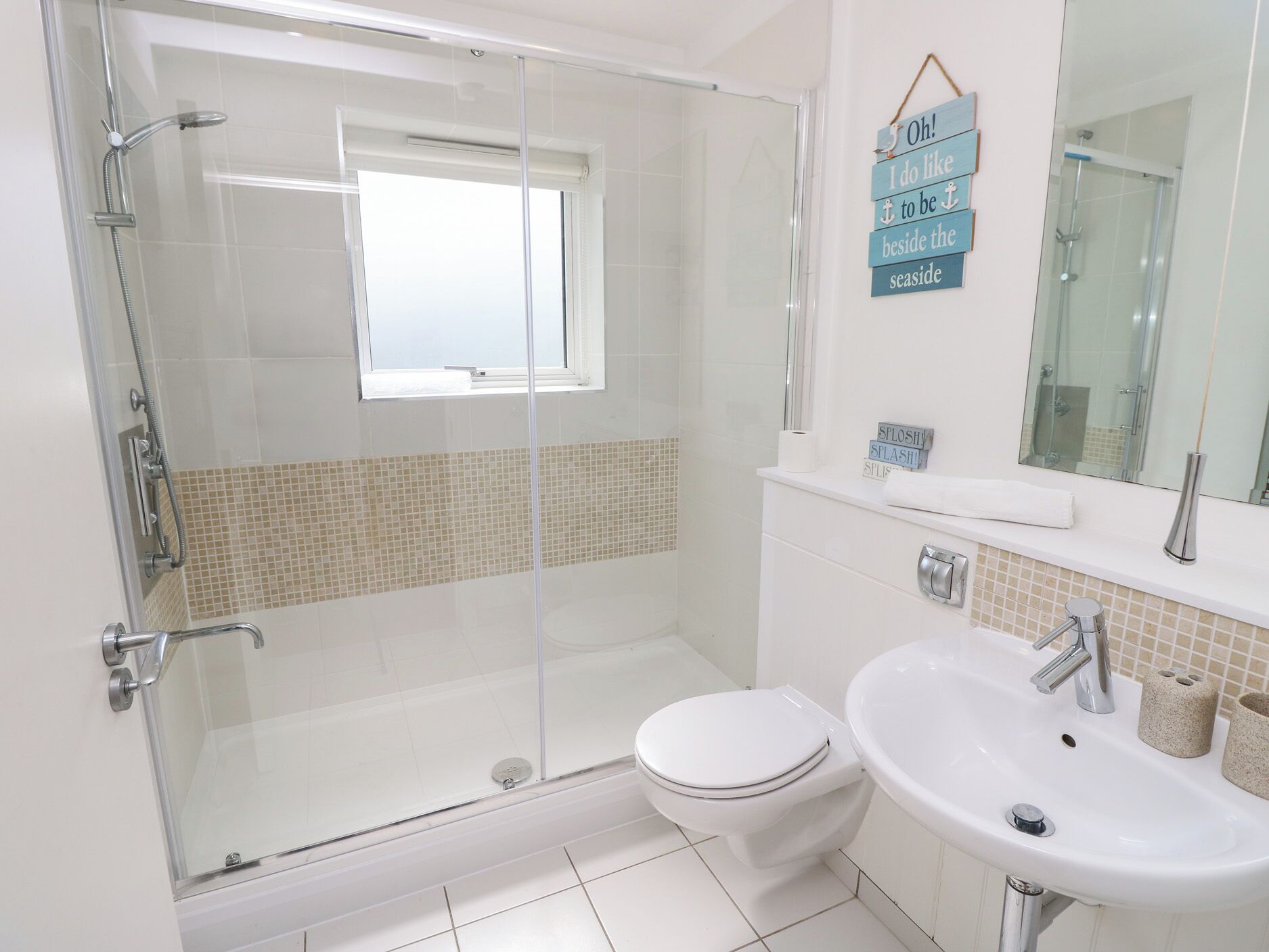 A modern bathroom with a glass-enclosed shower, a toilet, and a sink.