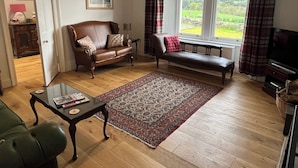 A living room with a brown leather sofa, a bench, a coffee table, and a television. - Ryehill With Fishing (Sanquhar)