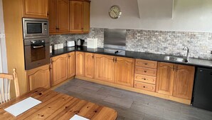 A kitchen with wooden cabinets, a microwave, oven, and a stainless steel sink. - Ryehill With Fishing (Sanquhar)
