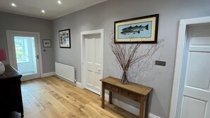 A hallway with wooden flooring, white doors, a radiator, and a framed fish painting on the wall. - Ryehill With Fishing (Sanquhar)