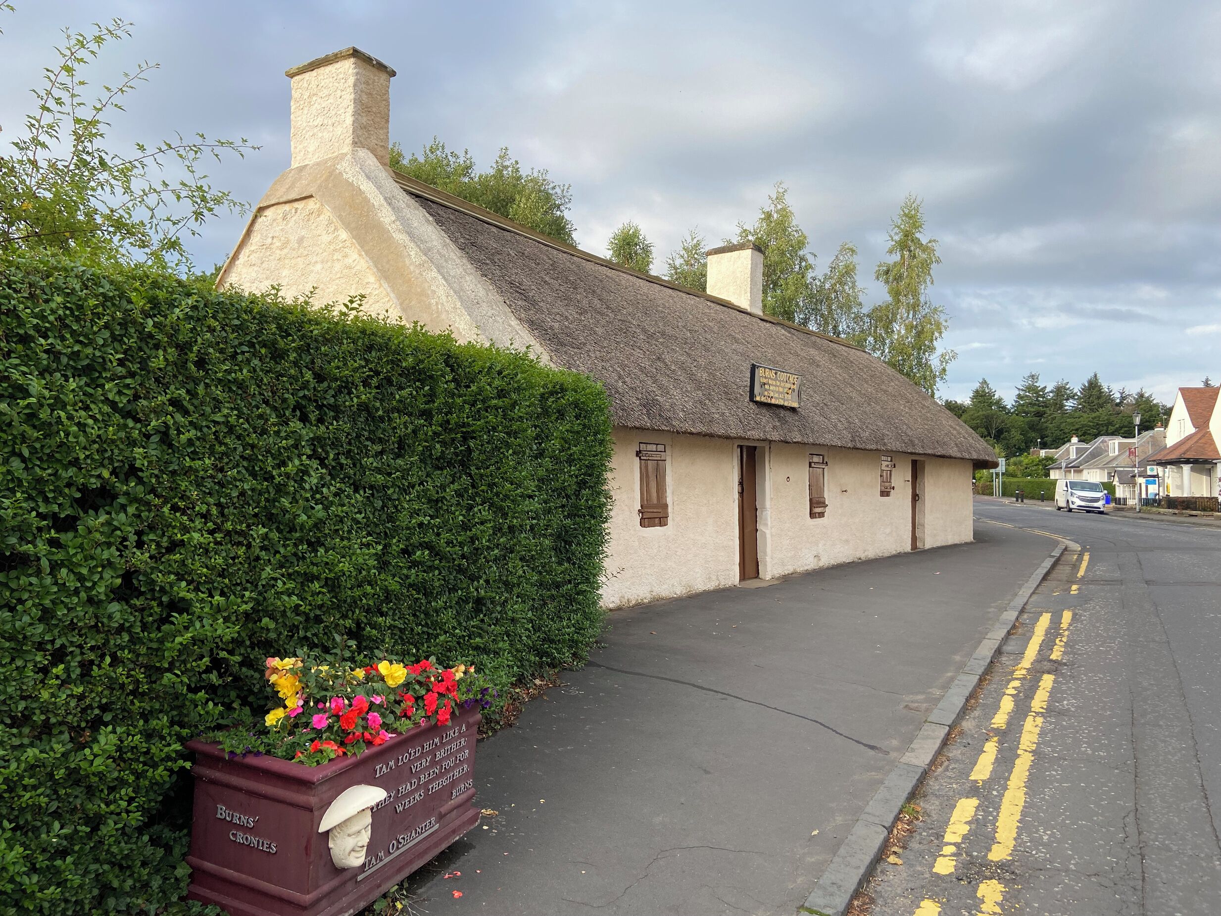 Une maison de campagne traditionnelle à toit de chaume, avec une enseigne indiquant qu’il s’agit d’une maison d’hôtes.