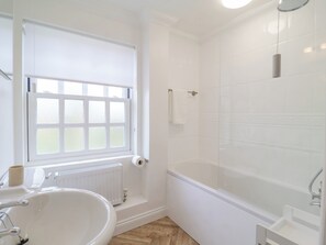 A bathroom with a bathtub, a window, a toilet, and a sink. - 23 Church Farm Lane (Halesworth)