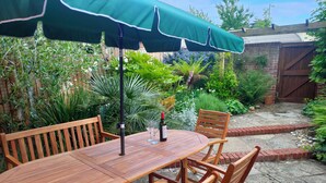 Un tavolo di legno con sedie e un ombrello verde in un giardino.
