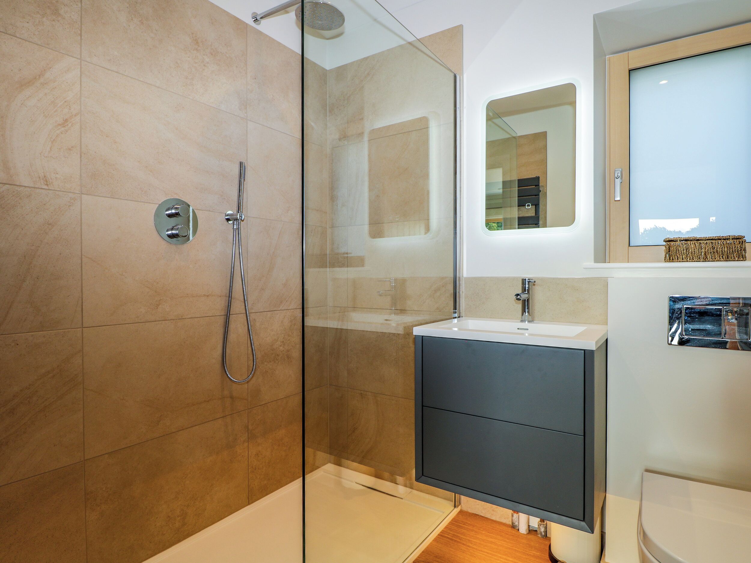 Une salle de bain moderne avec une douche à parois de verre, un meuble-lavabo aux tons foncés et un grand miroir au-dessus du lavabo.