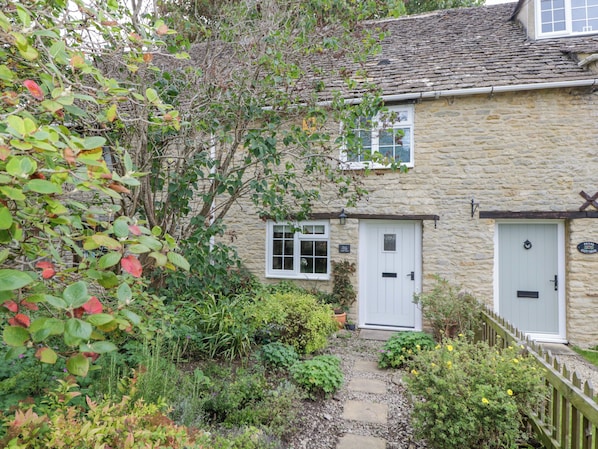 A stone cottage with a garden path leading to a white door. - Thorn Cottage (Fairford)