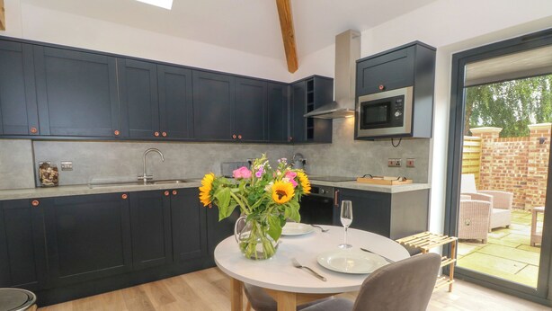 Een moderne keuken met donkere kastjes, een magnetron en een eethoek met een tafel en stoelen.