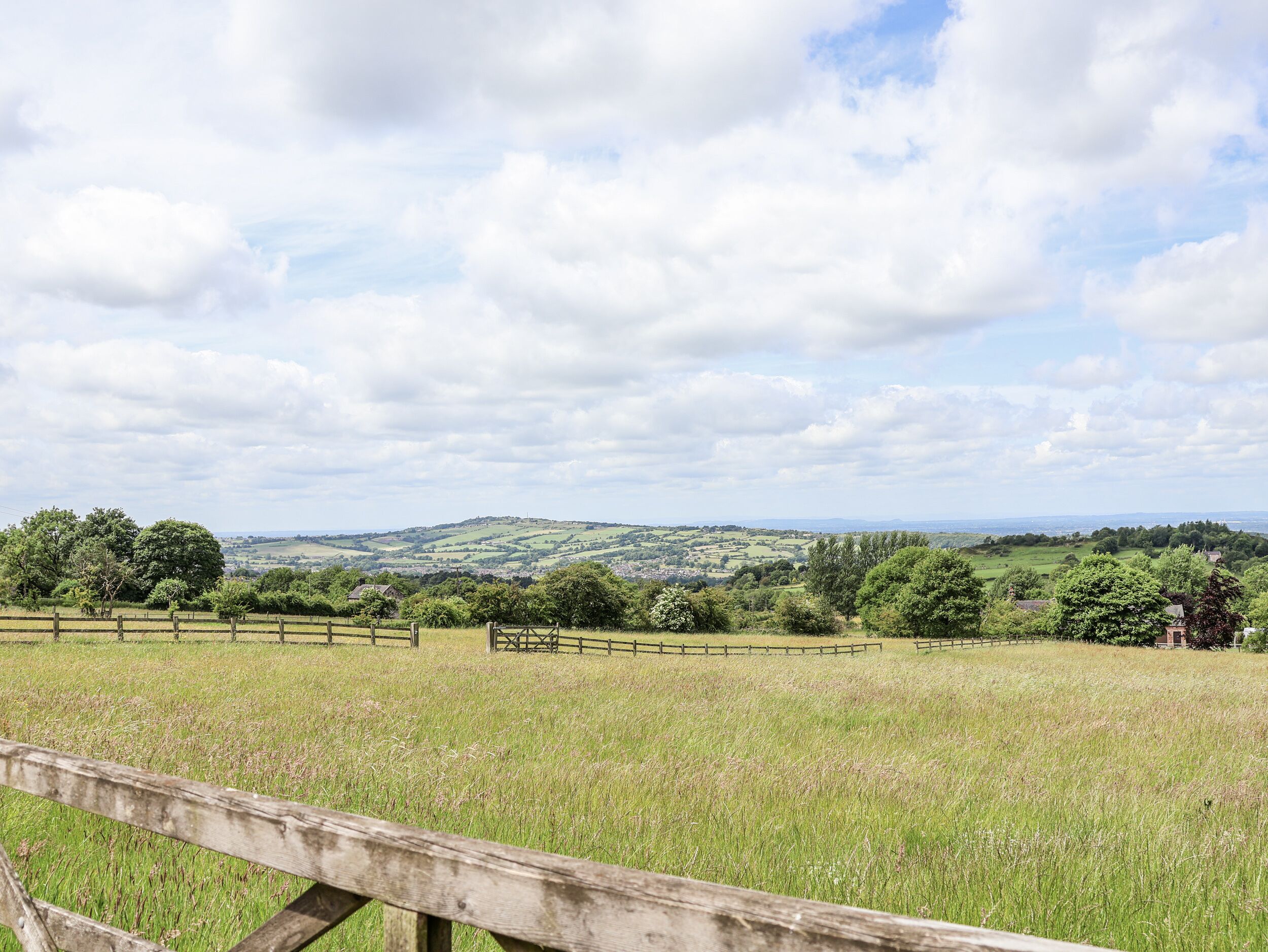 A rural landscape with rolling hills, a wooden fence, and a clear sky.