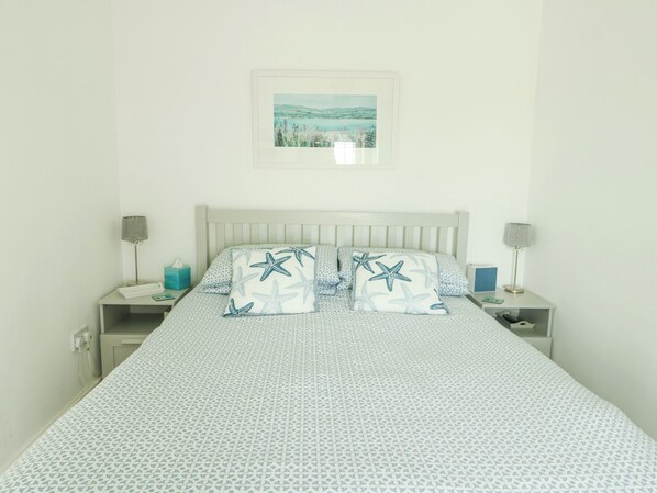 A bedroom with a bed, two nightstands, a lamp on each side, and a framed picture on the wall. - Bryn Tirion (Moelfre)