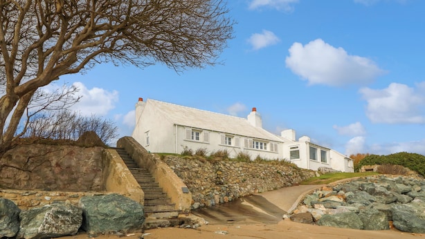 Una casa blanca con una escalera de piedra que lleva a una terraza de madera.