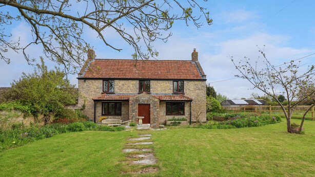 A stone house with a tiled roof, a front porch, and a stone pathway leading to the entrance. - Canny Croft (Bridgwater)