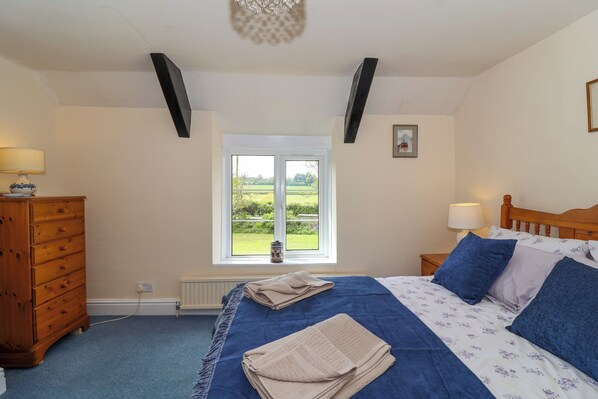 Un dormitorio con cama, cómoda, ventana y vistas al exterior.