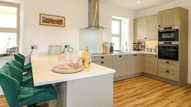Una cocina moderna con una isla central, suelo de madera y electrodomésticos integrados.