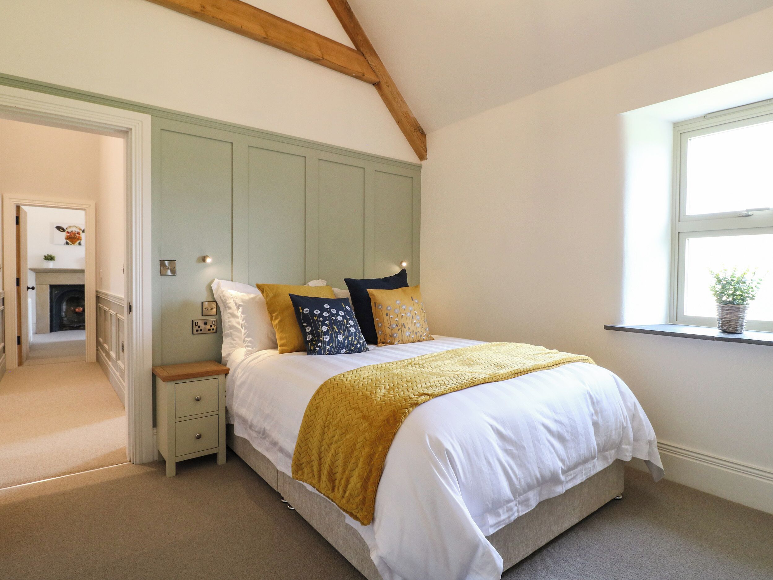 A bedroom with a bed, nightstands, a window, and a door leading to a hallway.