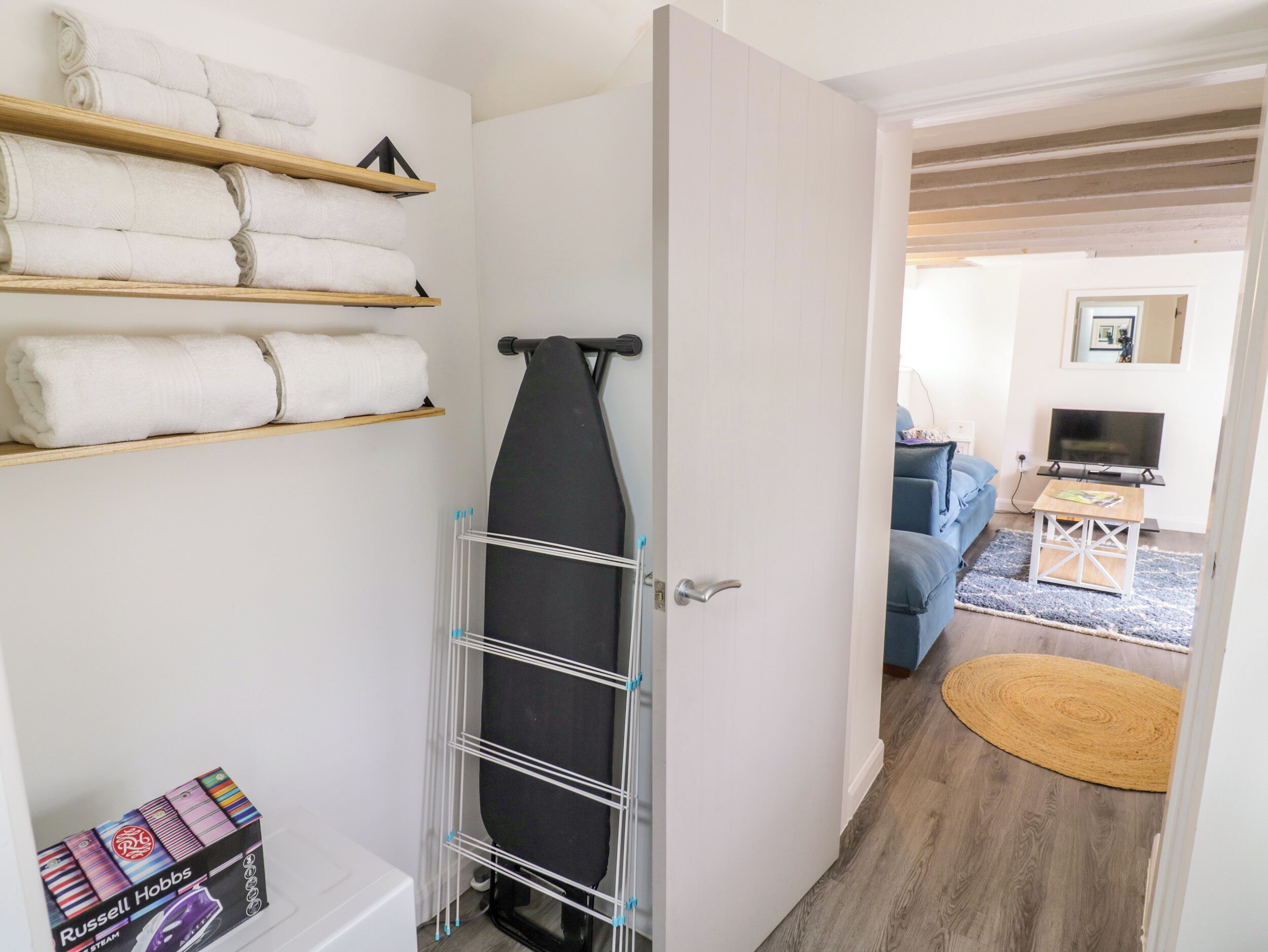 A room with a drying rack, a television, a sofa, and a small table with a magazine.