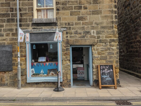 A stone building with a small shop entrance, a signboard for Italian Gelato, and a chalkboard sign advertising open hours. - Lark Rise (Alnwick)